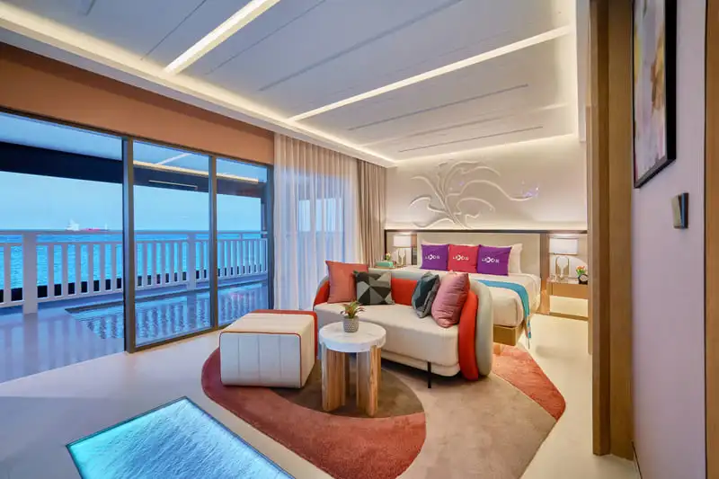 Lexis Hibiscus 2 overwater villa interior with king bed, sea-view balcony and glass floor panel